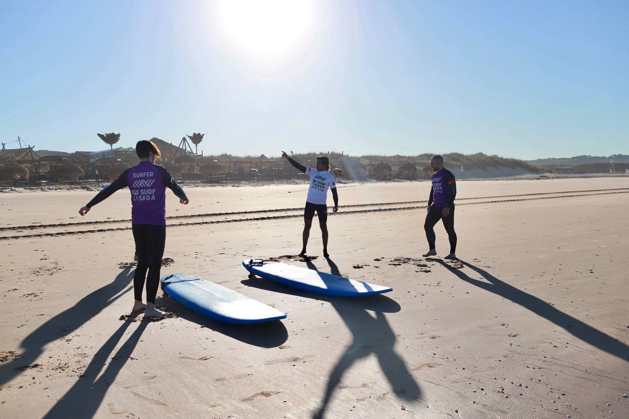 Participants practising their surfing stance on the beach