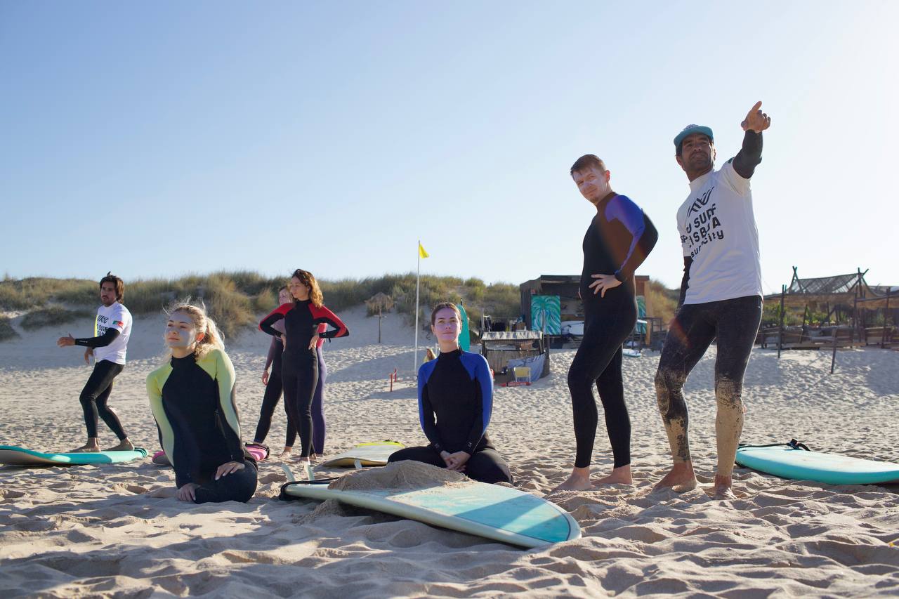 A Go Surf Lisboa instructor briefing the group on the beach