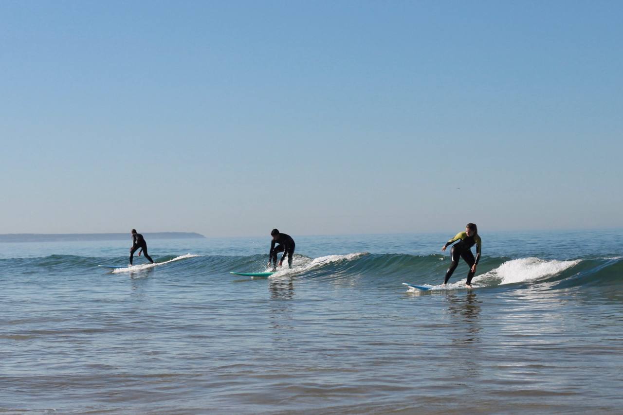 Three surfers riding the same wave together off the Portuguese coast