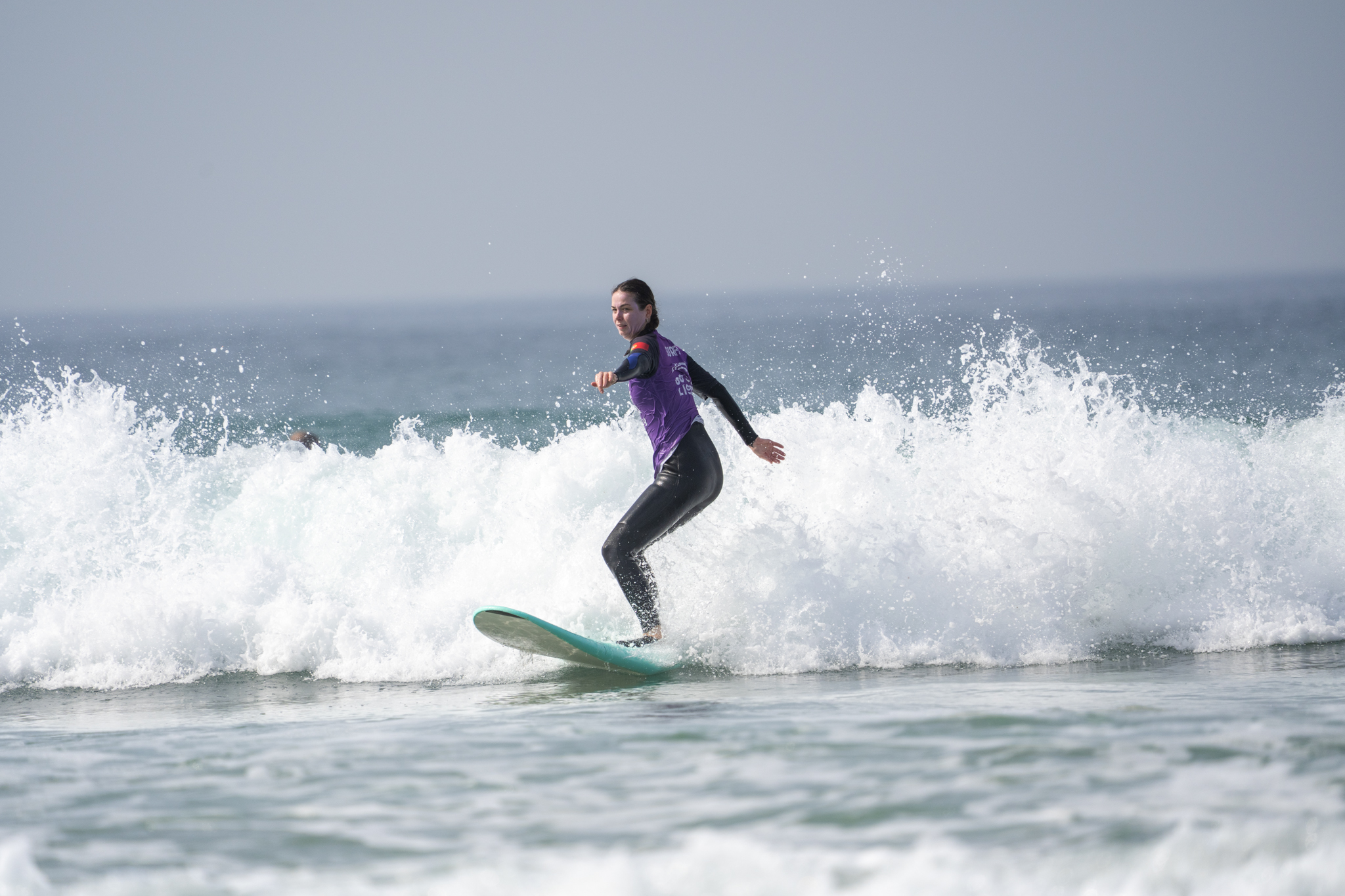 A participant balancing on a green surfboard in the waves